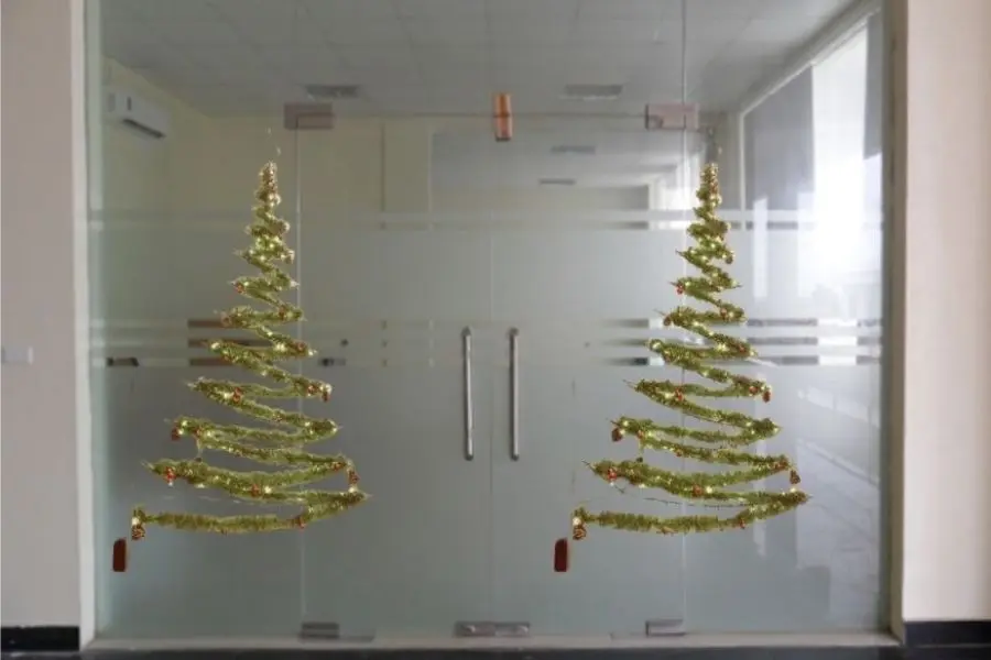 Cây thông Noel trang trí dây kim tuyến trên cửa kính lung linh.