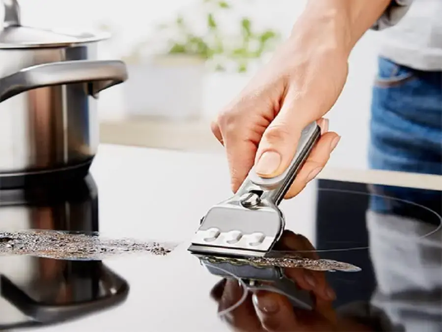 Dùng dao cạo bếp bẩn bám trên bề mặt kính của bếp hồng ngoại (nguồn: hangxachtayger.com)