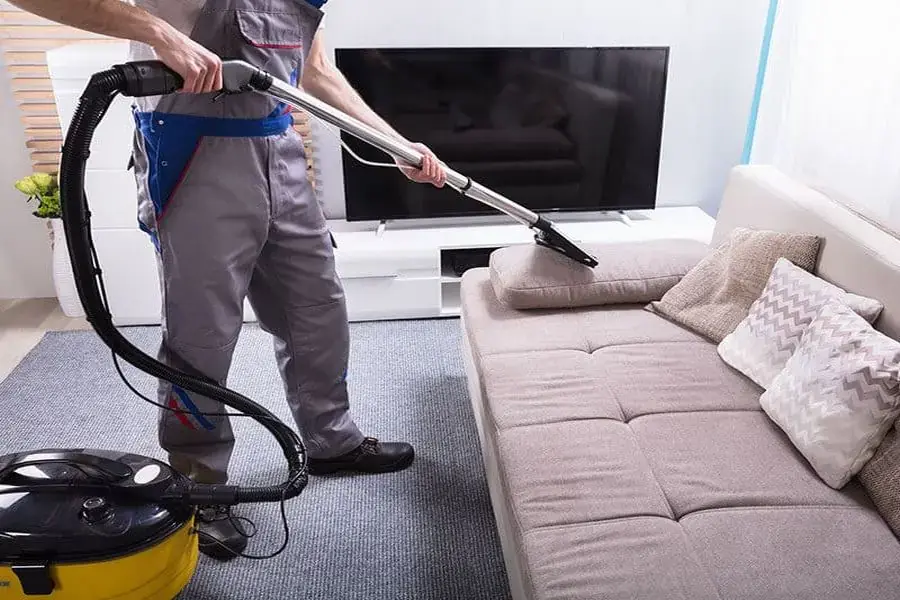 Dùng máy hút bụi để làm sạch bề mặt sofa 