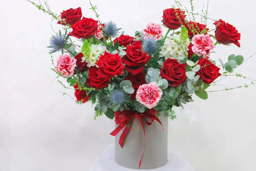 Hoa hồng và hoa cẩm chướng, điểm xuyết thêm vài cành lá xinh xắn.