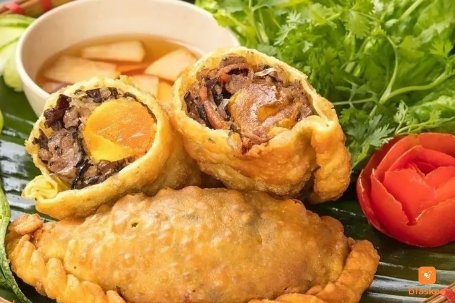 Bánh gối được cắt làm hai. Thấy rõ trứng, nhân thịt bên trong. Đặt trên 1 cái bánh gối hoàn chỉnh