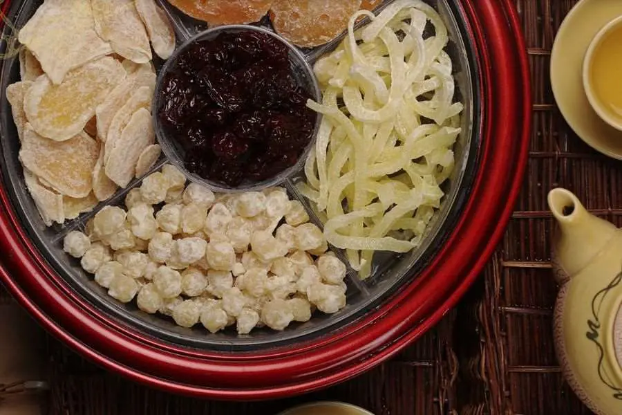 Mâm bánh kẹo đãi khách ngày Tết thường có các loại mứt, hạt, trái cây sấy, được bày ra khay đặt trên bàn trà.