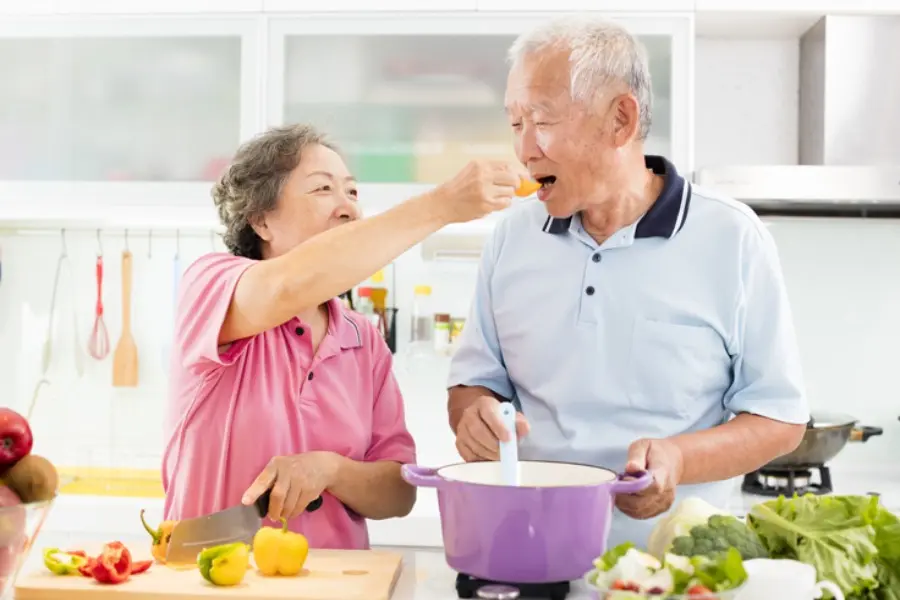 Cụ bà đang đút cam cho cụ ông