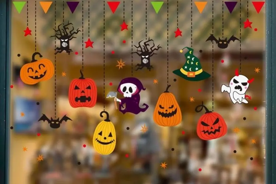 Trang trí Halloween trên cửa kính bằng các hình bí ngô, cây khô, thây ma.