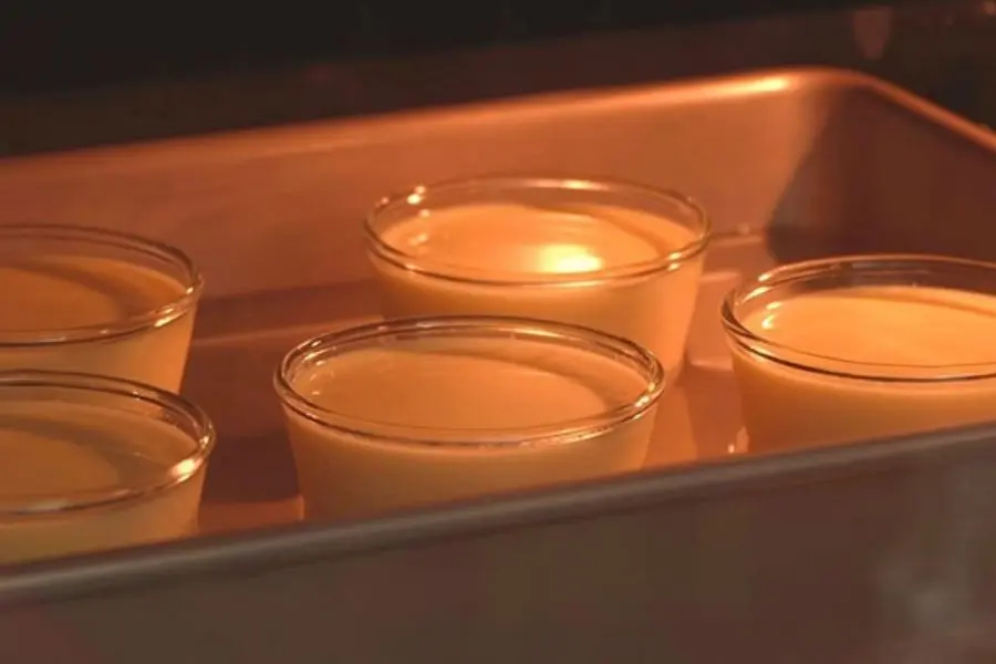 Khuôn bánh flan trong khay nướng đặt trong lò nướng