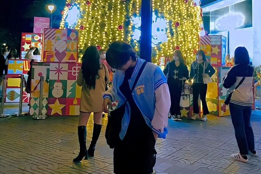 Đứng trước, lấy background là cây thông Noel phía sau.