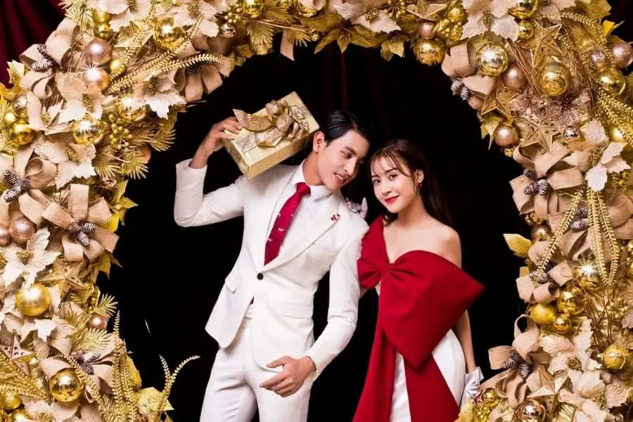 Concept chụp ảnh Noel theo phong cách rạng rỡ cho các cặp đôi tại studio cùng với vòng nguyệt quế khổng lồ.