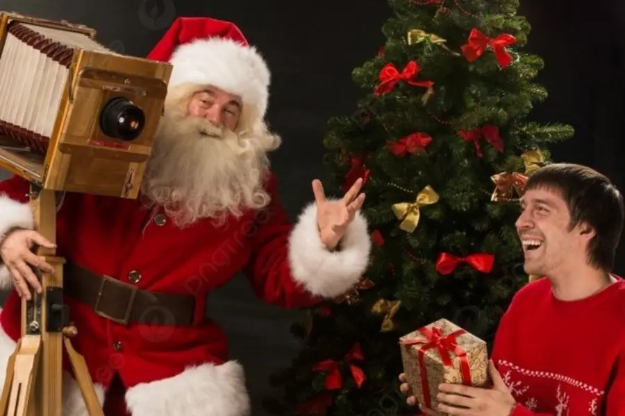 Ông già Noel chụp ảnh nhí nhảnh bên chiếc máy ảnh cổ.