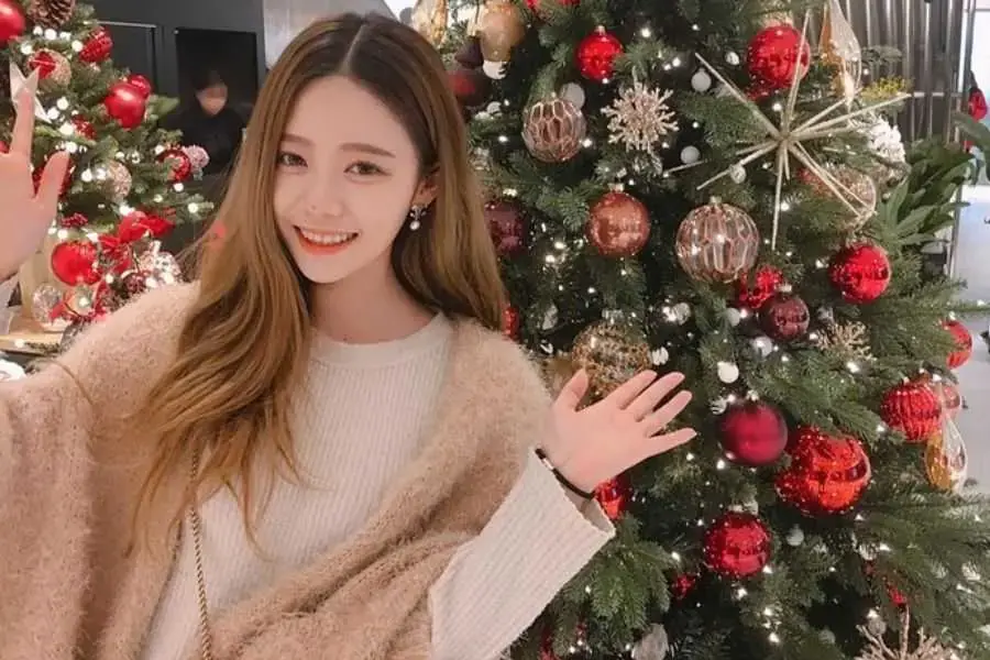 Đứng quay lưng vào cây thông Noel với biểu cảm dễ thương.