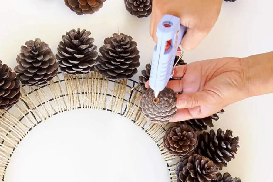 Lần lượt dán trái thông lên khung vòng Giáng Sinh.