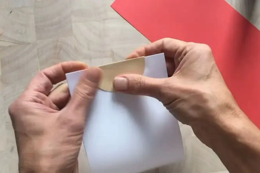 Dán phần mặt vào tờ giấy đã uốn.