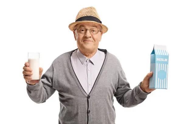 Mature man holding a glass of milk and a milk carton isolated on white background