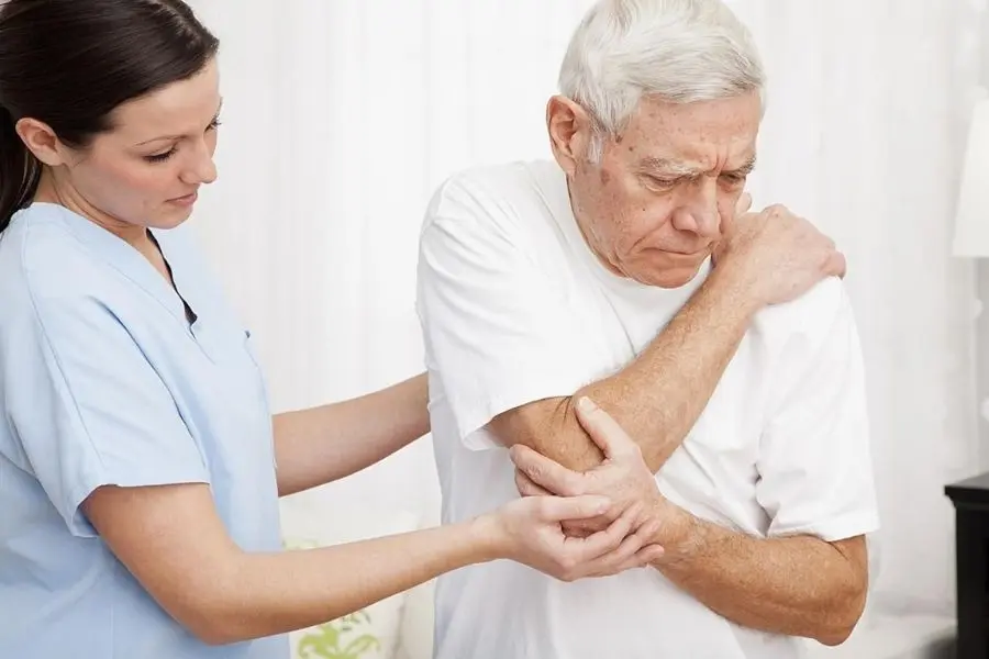Y tá đang hỗ trợ cụ già bị đau vai