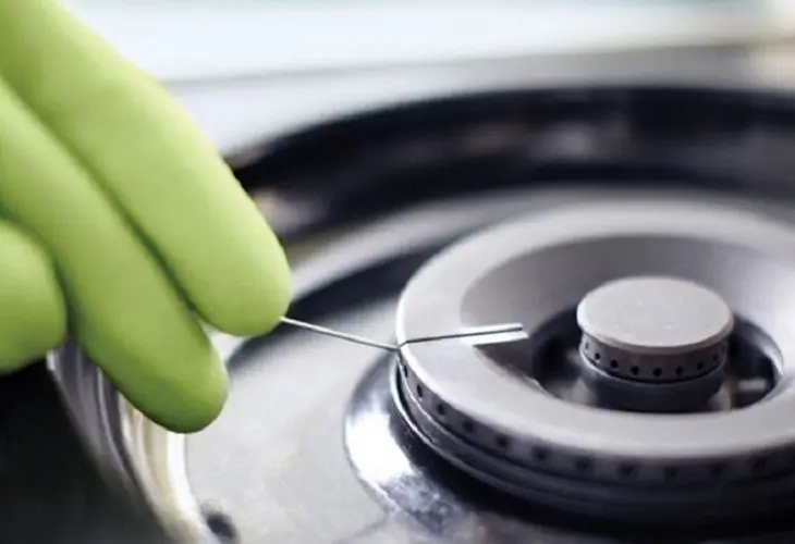 Use a small needle to clean each burner hole