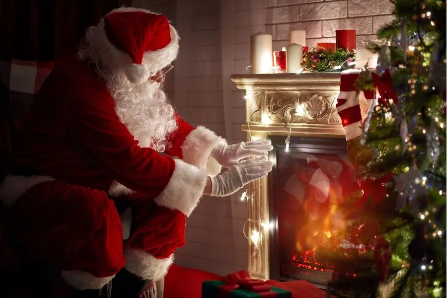 Hình ảnh ông già Noel sưởi ấm bên lò sưởi.