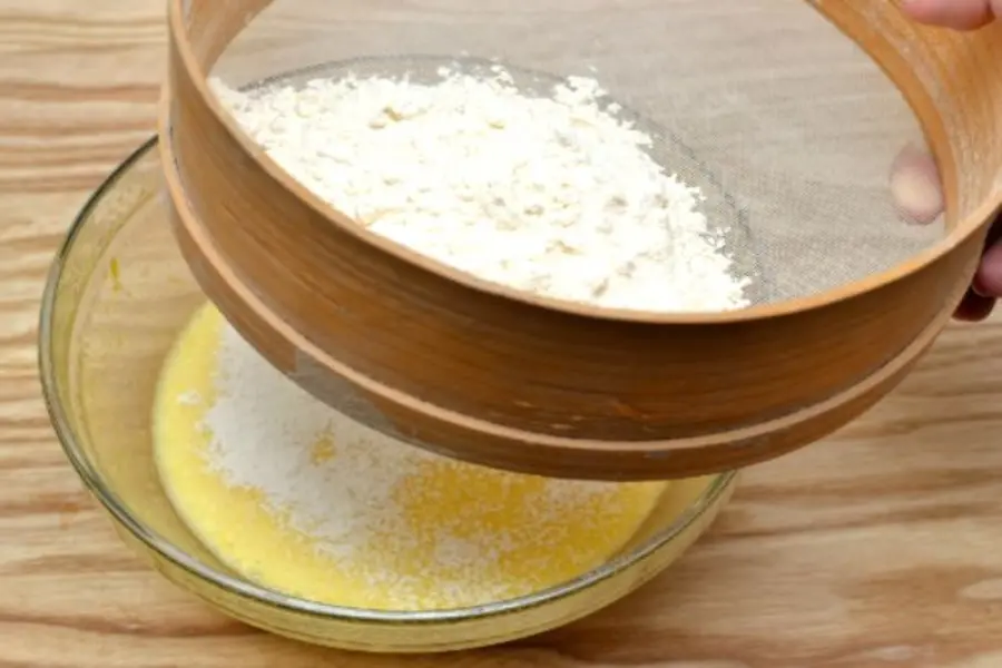 Rây bột vào hỗn hợp trứng đã trộn đều