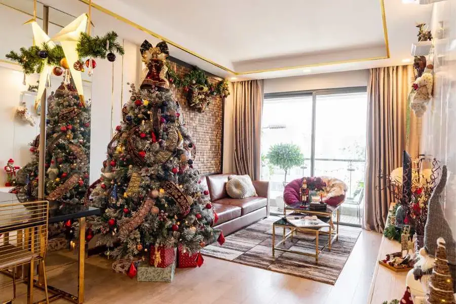 Cây thông Noel được trang trí thêm một số dây kim tuyến và trái chậu đặt tại khu vực phòng khách vô cùng đẹp mắt.