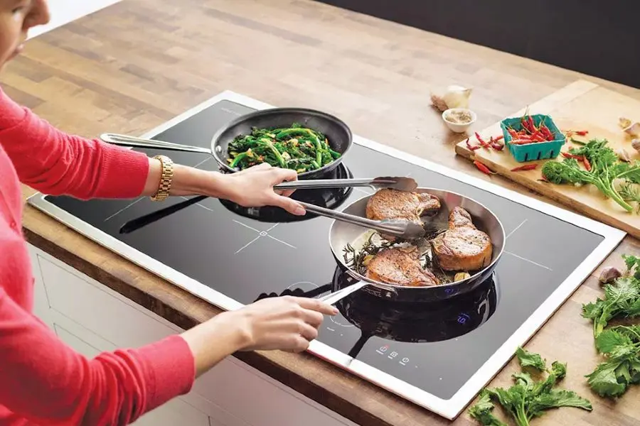 người đang nấu thức ăn trên bếp từ