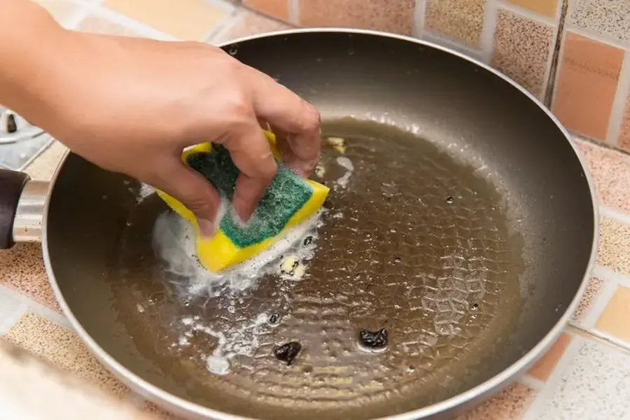 Dùng miếng bọt biển để đánh bay thức ăn còn sót lại trên chảo 