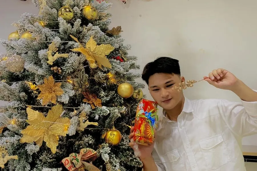 Ngồi tạo dáng cùng phụ kiện cây thông Noel.
