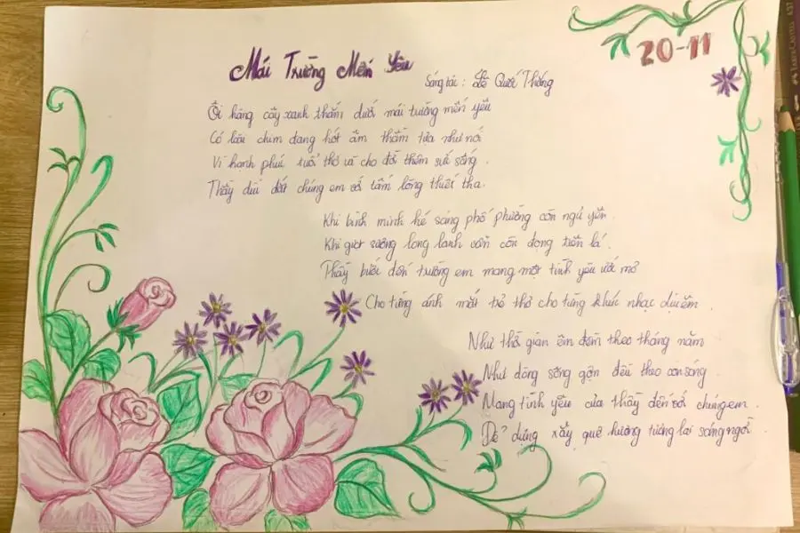 Mẫu trang trí bào tường 20 11 trên giấy a4 vẽ tay khung viền hoa hồng cùng bài thơ “Mái trường mến yêu” của tác giả Lê Quốc Thắng.