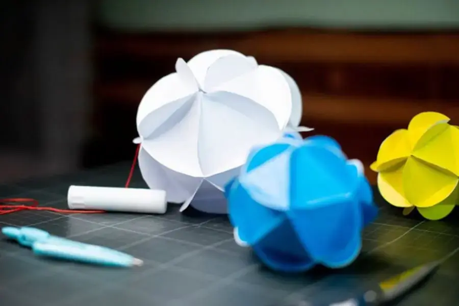 Gấp tấm bìa cứng theo hình xếp quạt, cắt bỏ các phần đầu và thắt nút để tạo thành đèn lồng