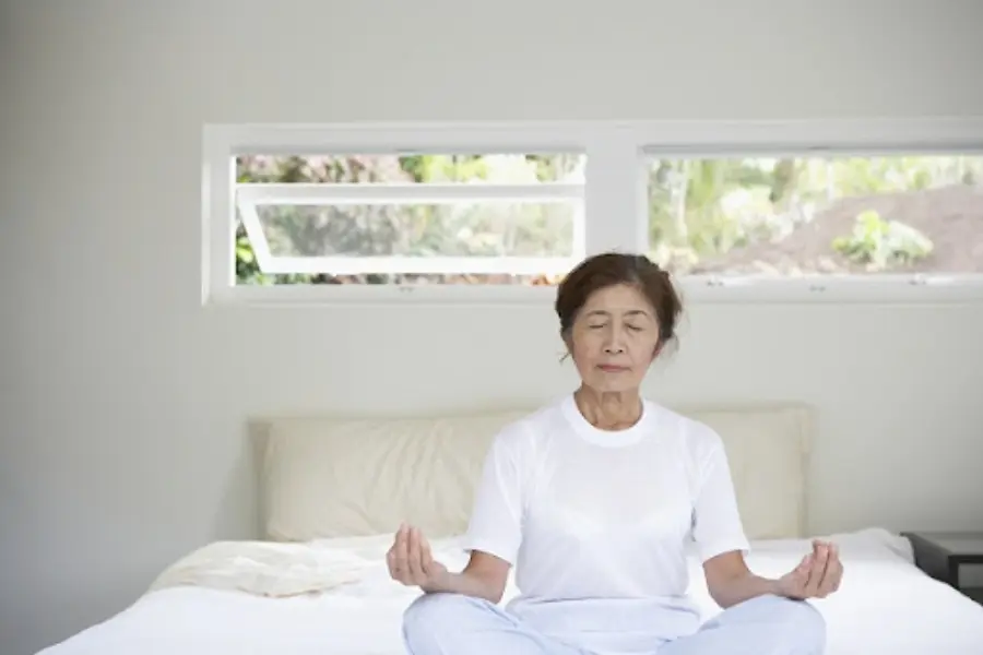 Cụ bà đang ngồi thiền trên giường ngủ