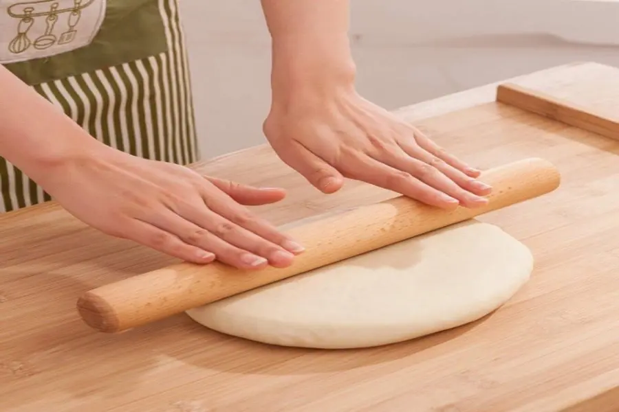 Dùng dụng cụ cán bột mỏng từ trong ra ngoài rồi cuộn lại.