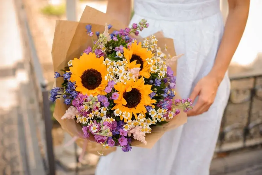 Hình ảnh bó lấy 3 hoa hướng dương làm chủ đạo, đan xen hoa cúc họa mi và các loại hoa nhỏ khác.