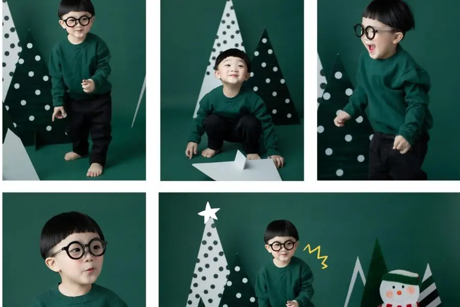 Cho bé mặc áo xanh đậm chụp cùng phông nền xanh đậm để tạo concept Noel xanh.