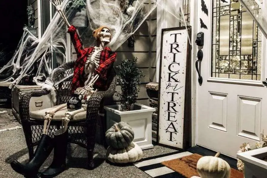 Mẫu trang trí cửa quán cà phê Halloween với bộ xương và bí ngô.
